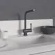 Schwarze Küchenarmatur von Ideal Standard mit hohem Auslauf und seitlichem Hebel, montiert auf einer hellen Arbeitsfläche, neben einer Schüssel und Geschirr.
